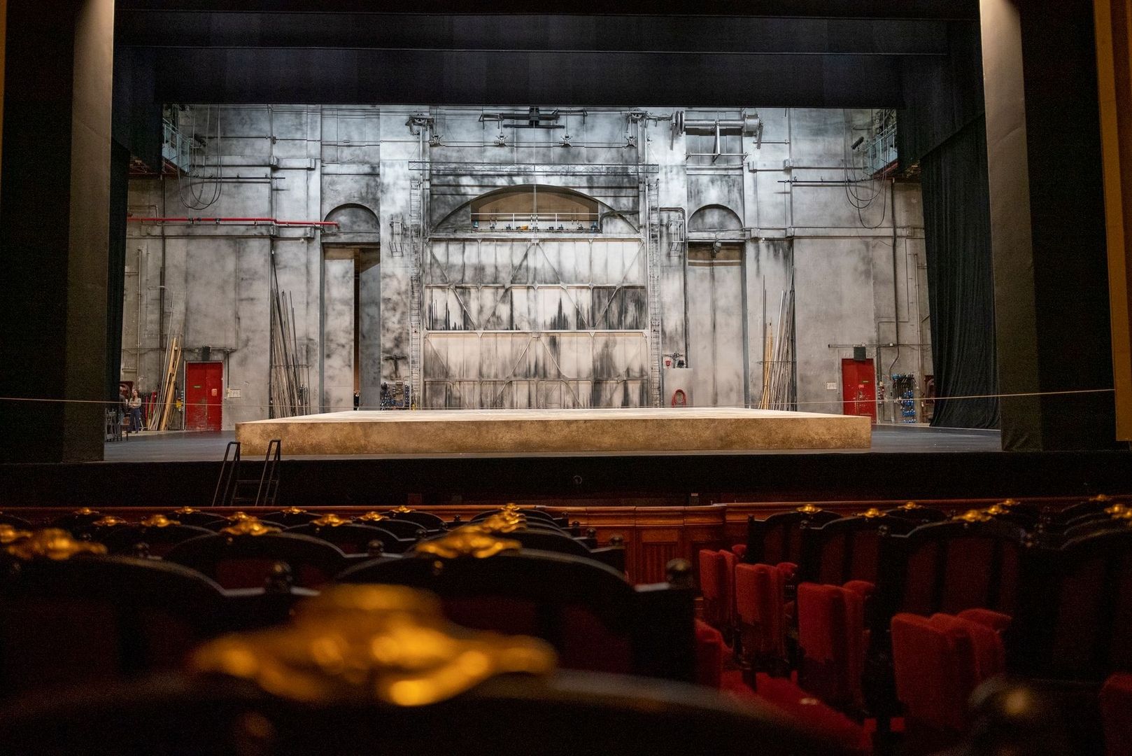 Blick auf eine historische Theaterbühne mit Kulisse und roten Zuschauersitzen